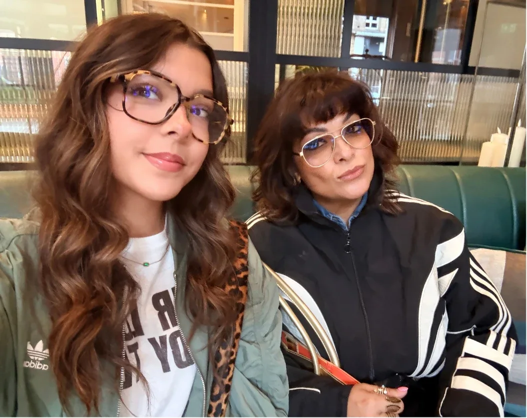 Nishma and Anushka in glasses, pulling faces in a café