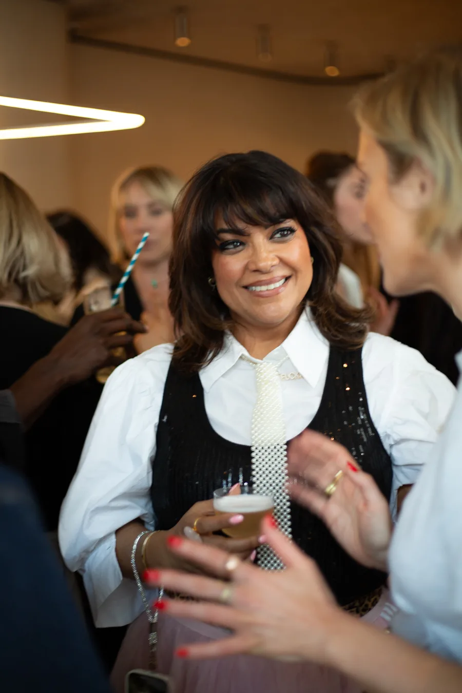 Nishma laughing with guests over a drink at an evening event
